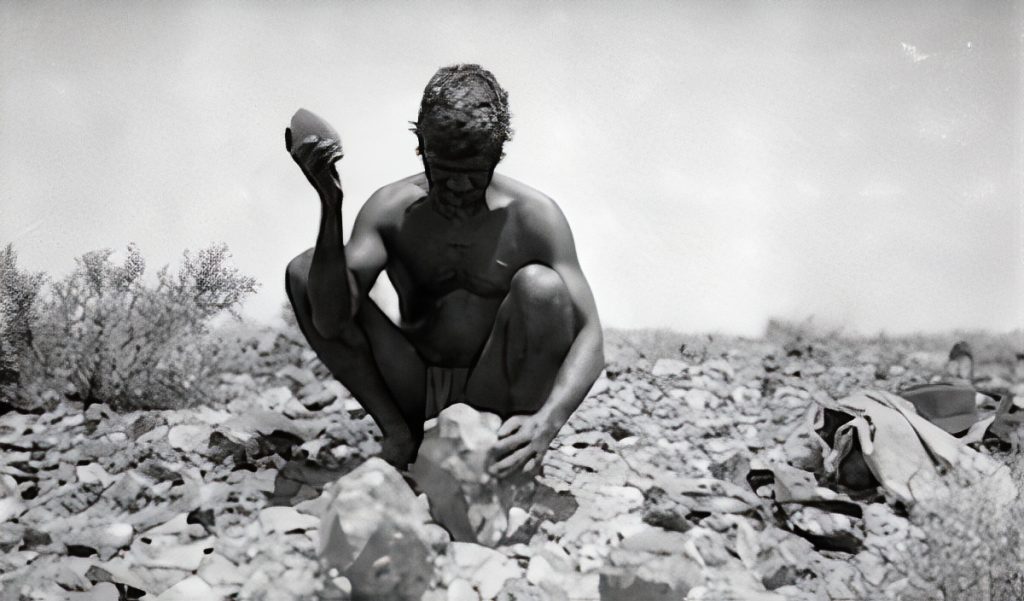Using a hammer stone to break off flakes from a core. These flakes are then fashioned into knives and scrapers.